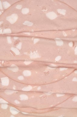 İnce dilimlenmiş pembe mortadella sosislerinin detaylı dokusunu ve beyaz yağ lekelerini gösteren yakın çekim makrosu tüm çerçeveyi dolduruyor.