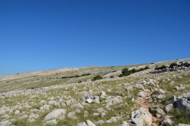 Hırvatistan 'ın Krk adasındaki Ay Dağı' nın kayalık manzarası açık mavi bir gökyüzü altında