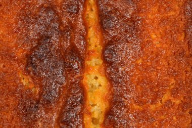 Fırınlanmış limonlu kekin altın kahverengi kabuğunun tam kare makro görüntüsü tatlı tatlıların gözenekli ve dokulu yüzeyini içerir.