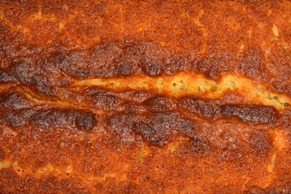 Fırınlanmış limonlu kekin altın kahverengi çıtır çıtır kabuğunun tam kare makro görüntüsü tatlı tatlıdaki gözenekli ve dokulu yüzeyi gösteriyor.