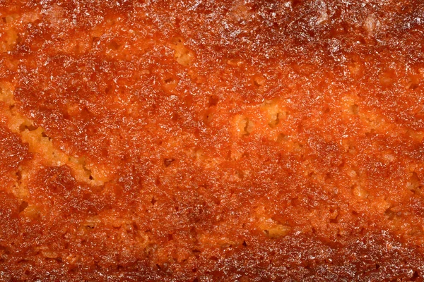 Fırınlanmış limonlu kekin altın kahverengi çıtır çıtır kabuğunun tam kare makro görüntüsü tatlı tatlıdaki gözenekli ve dokulu yüzeyi gösteriyor.