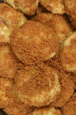 Altın tost kırıntılarıyla kaplanmış ve metal bir kapta servis edilen geleneksel patates erikli hamur köftelerinin dikey yakın çekimi.