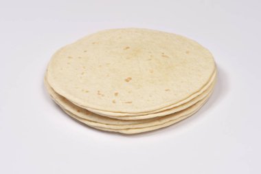 Düz beyaz bir arkaplandan çekilen küçük yuvarlak buğday tortillası yığını.