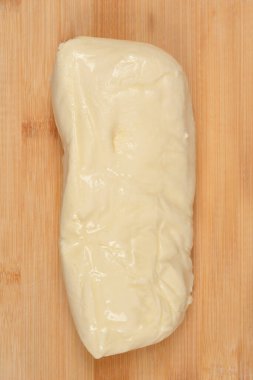 Doğal bambu kesme tahtasına yerleştirilmiş yumuşak beyaz mozzarella peyniri.