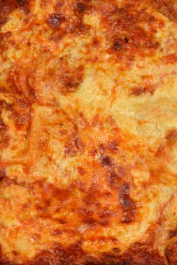 Yeni pişmiş bir lazanyanın detaylı makro çekimi çıtır çıtır kahverengi peynir kabuğu ve bol köpüklü et sosu dokusunu gösteriyor.