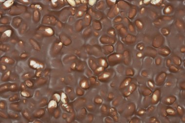 Çırpılmış pirinç parçalarıyla dolu sütlü çikolatanın engebeli yüzeyini yakından görmek zengin bir kahverengi gıda dokusu yaratır.