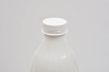 Plastik bir şişenin üst kısmının yakın çekim görüntüsü. Açık gri arka planda izole edilmiş bir vida kapağı var.
