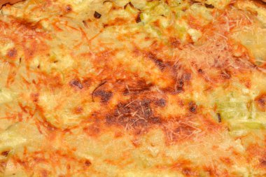 Fırında yeni pişmiş pırasa Graten 'in detaylı görüntüsü. Fırın kabuğundaki altın kahverengi peynir kabuğu ve kremalı sebze dokusunu gösteriyor.