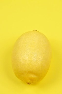 Tek bir parlak sarı limon eşleşen sarı bir yüzey üzerinde yoğunlaşır ve canlı bir tek renkli kompozisyon oluşturur..