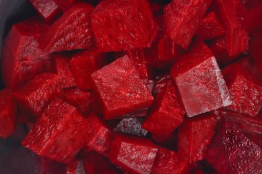 Detaylı bir makro çekim, tüm çerçeveyi dolduran taze doğranmış pancar pancar küplerinden oluşan karanlık, canlı bir yığın yakalar.