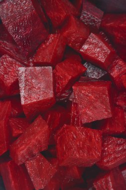 Dramatik, karanlık bir dikey çekim, taze, taze doğranmış pancar küplerinin zengin, ıslak dokusunu ve koyu kırmızı rengini ön plana çıkarıyor.