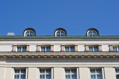 Beyaz tarihi bina cephesinde birkaç sıra pencere ve açık mavi gökyüzüne karşı üç farklı kemerli yatakhane penceresi yer almaktadır.