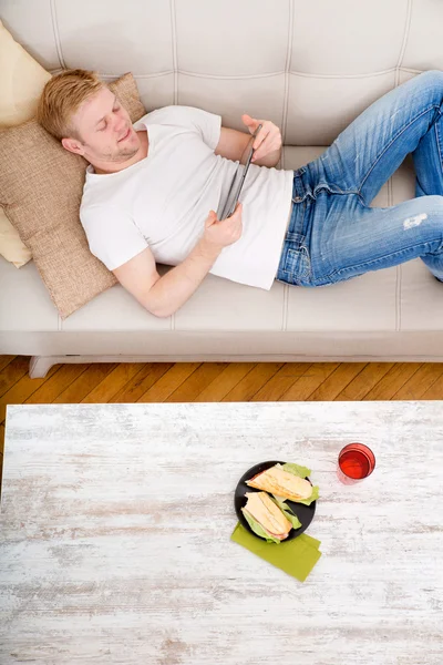 Jongeman die thuis een tablet gebruikt — Stockfoto