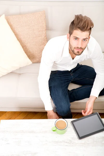 Jonge man met tablet op Bank — Stockfoto