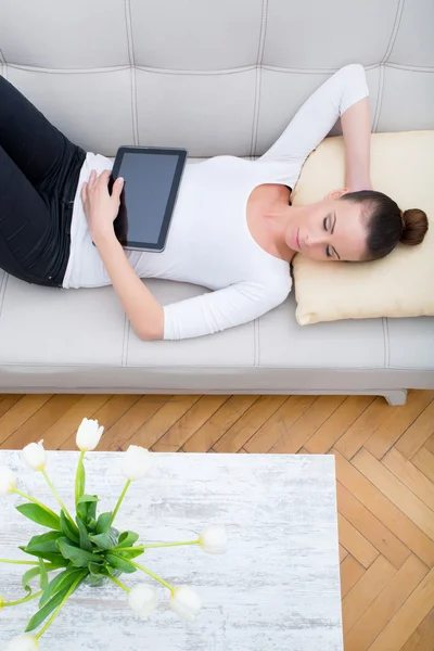 Giovane donna con un Tablet PC sul divano — Foto Stock