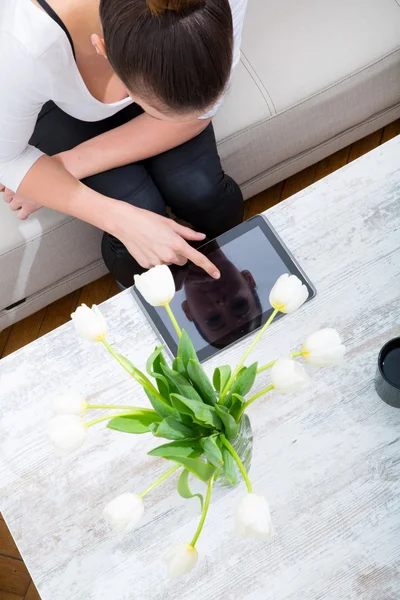 Mujer joven con un Tablet PC en el sofá —  Fotos de Stock