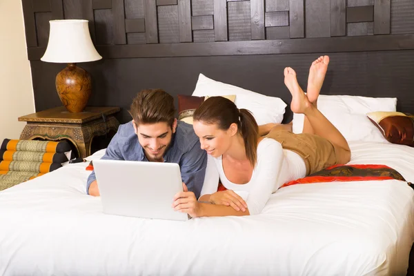 Νεαρό ζευγάρι χρησιμοποιώντας ένα φορητό υπολογιστή σε ένα δωμάτιο ξενοδοχείου Ασίας — Φωτογραφία Αρχείου
