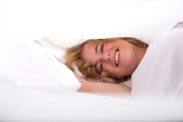 Jonge vrouw verbergen in Bed onder de lakens — Stockfoto