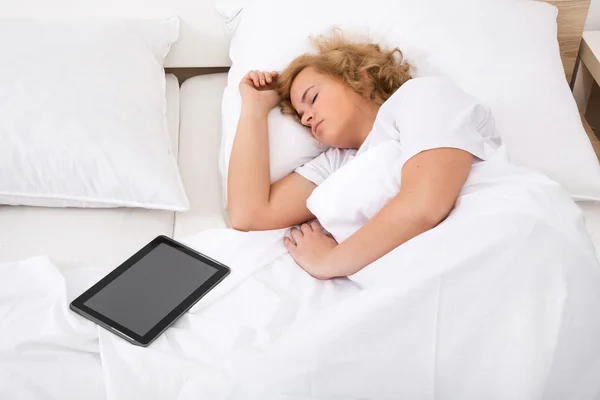 Jovem mulher dormindo na cama com um Tablet PC — Fotografia de Stock