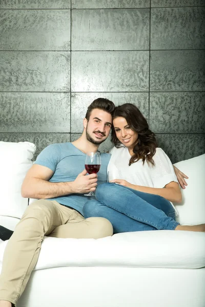 Hermosa pareja disfrutando de una copa de vino en el sofá — Foto de Stock