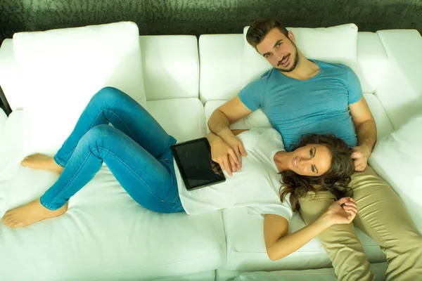 Young couple using a Tablet PC together on the Sofa at home — Stock Photo, Image