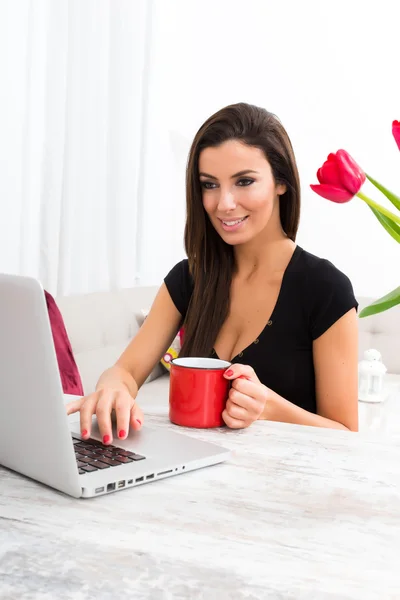 Jonge mooie vrouw met behulp van een laptop thuis — Stockfoto