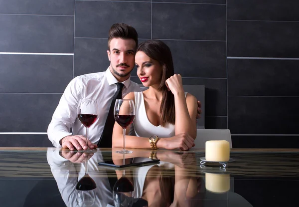 A romantic couple with a glass of wine in the dining room — Stock Photo, Image