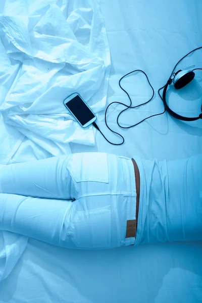 Mujer en la cama con los auriculares y un smartphone — Foto de Stock