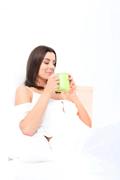 Mooie jonge vrouw, met haar eerste koffie in bed — Stockfoto