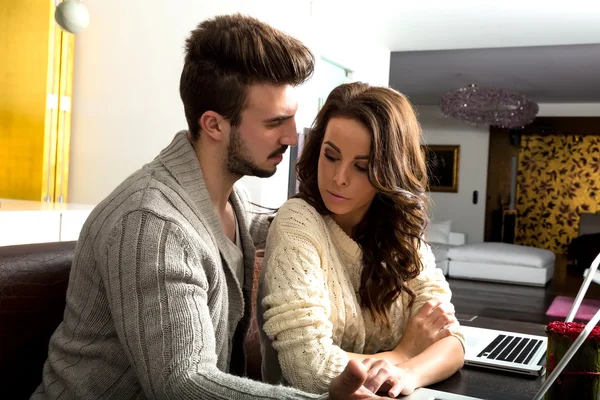 对年轻的夫妇讨论笔记本电脑在家里的一台电脑前 — 图库照片#