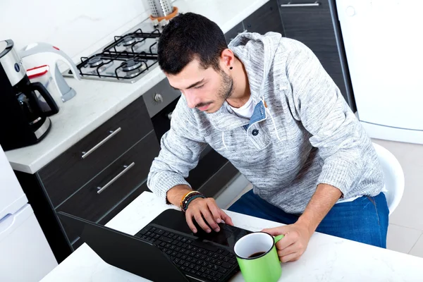Ung man med laptop i köket — Stockfoto