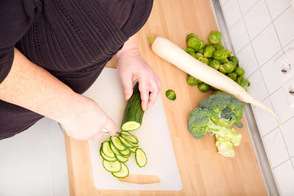 Woman cutting cucumber — Stock Photo, Image