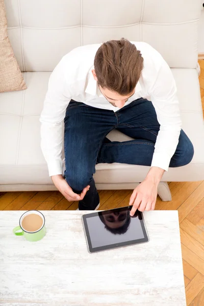 Ung man med tablett på soffan — Stockfoto