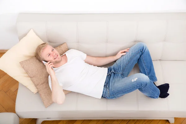 Young man talking on the phone at home — Stock Photo, Image