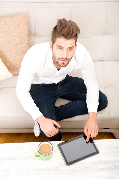 Jovem com tablet no sofá — Fotografia de Stock