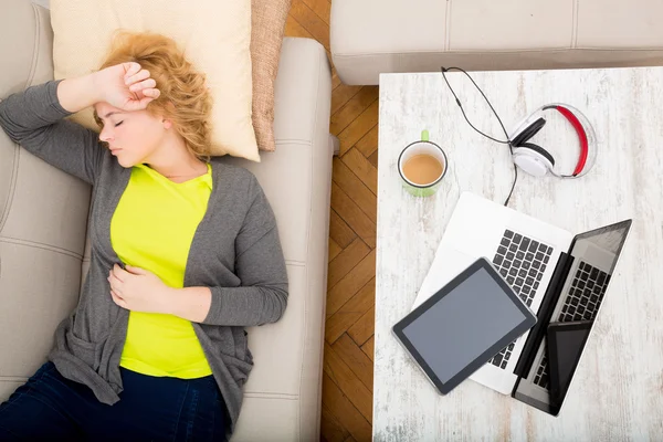 Jonge vrouw op de bank met gadgets — Stockfoto