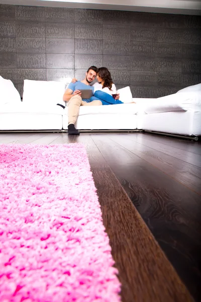 Casal jovem usando um Tablet PC juntos no sofá em casa — Fotografia de Stock