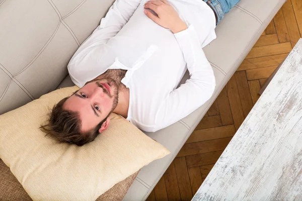 Молодой человек отдыхает на диване — стоковое фото
