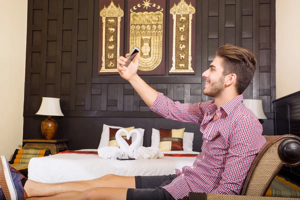 Mladý muž v hotelovém pokoji s ohledem selfie — Stock fotografie