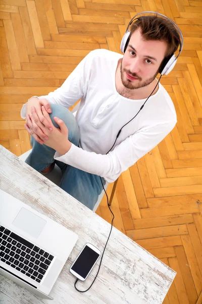 Ung man lyssnar musik på hans Laptop — Stockfoto