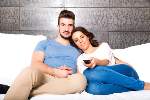 Pareja joven viendo televisión juntos en el sofá — Foto de Stock