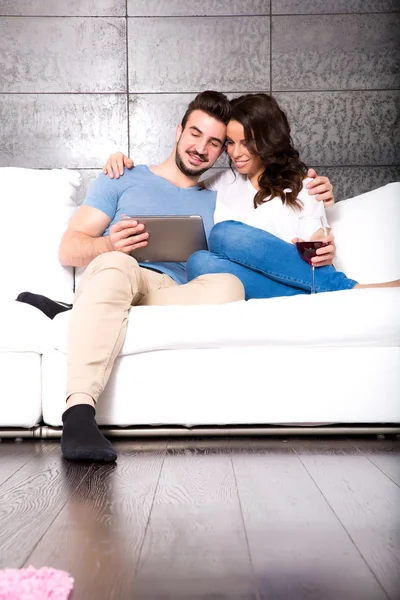 Young couple using a Tablet PC together on the Sofa at home — Stock Photo, Image