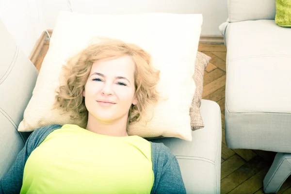 A young smiling woman relaxing on the sofa. — Stok fotoğraf