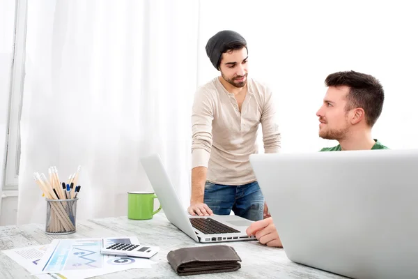 To medarbeidere diskuterer noe på kontoret. – stockfoto