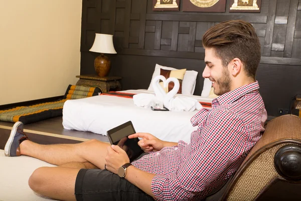 Young man using a tablet pc in a asian hotel room — Stock Photo, Image