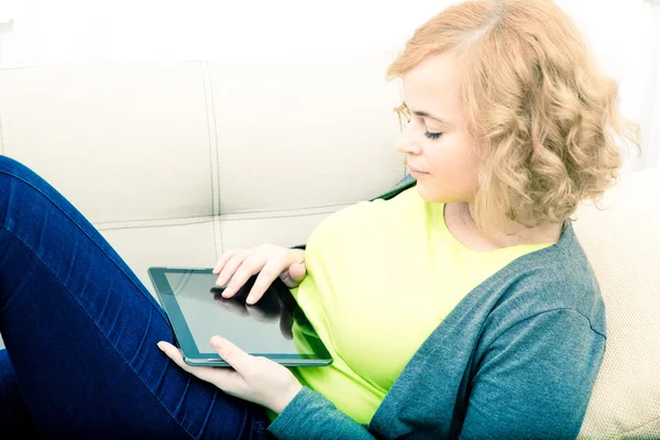 Mujer joven relajándose con una tableta PC en el sofá — Foto de Stock