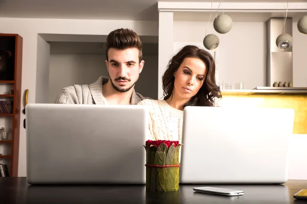 Pareja joven frente a sus computadoras portátiles en casa —  Fotos de Stock