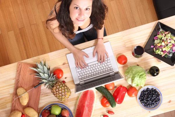 Frau benutzt Laptop beim Kochen — Stockfoto