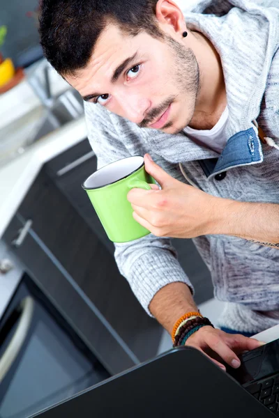 Young man with laptop in the kitchen — Stock Photo, Image