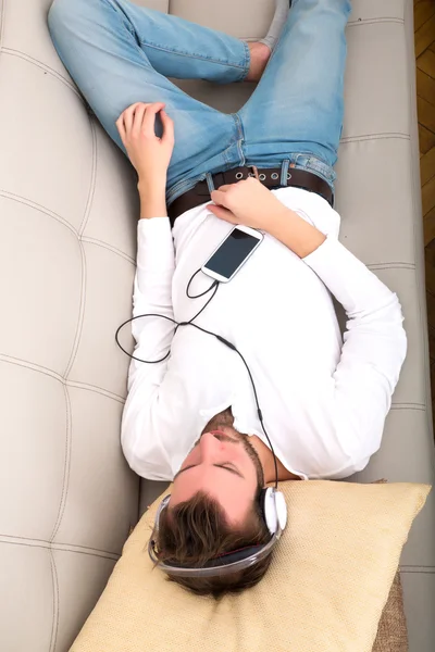 Young man listening to music on the sofa — Stock Photo, Image